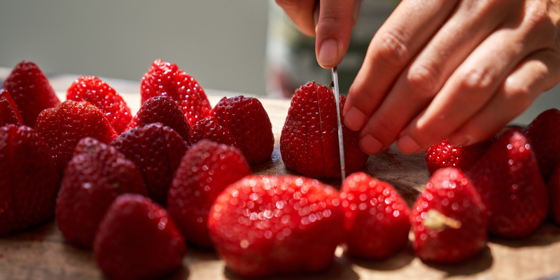 Slicing fresh, ripe strawberries is the first step to releasing their sweet juices for the shrub maceration process.
